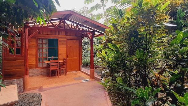 A wooden cabin with a porch, surrounded by lush greenery. - Jardín entre Montañas (Bijagua)