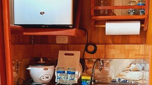 A compact kitchen with a built-in microwave, a sink, and a wooden shelf above. - Jardín entre Montañas (Bijagua)