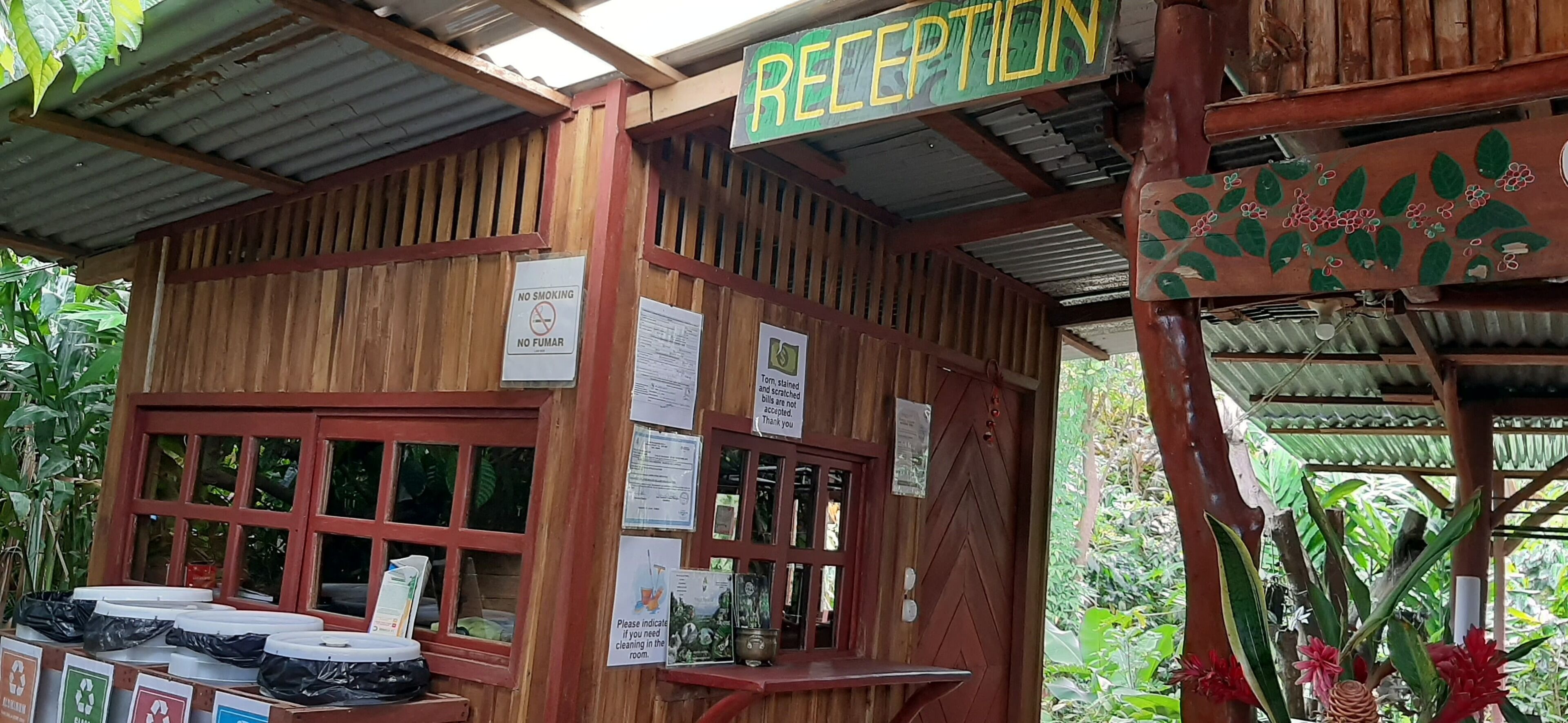 A wooden reception area with a sign reading "RECEPTION," a no smoking sign, and various informational notices.