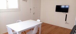 Enjoy meals and entertainment in this room with a table and chairs, a flat-screen TV, and a door with a simple handle.