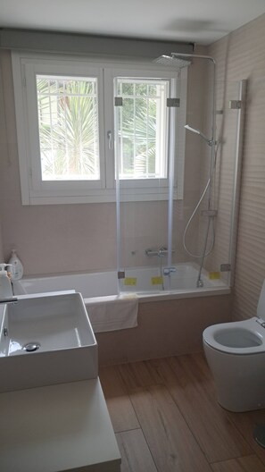 Bathroom features a large window, white sink, bathtub, and toilet.