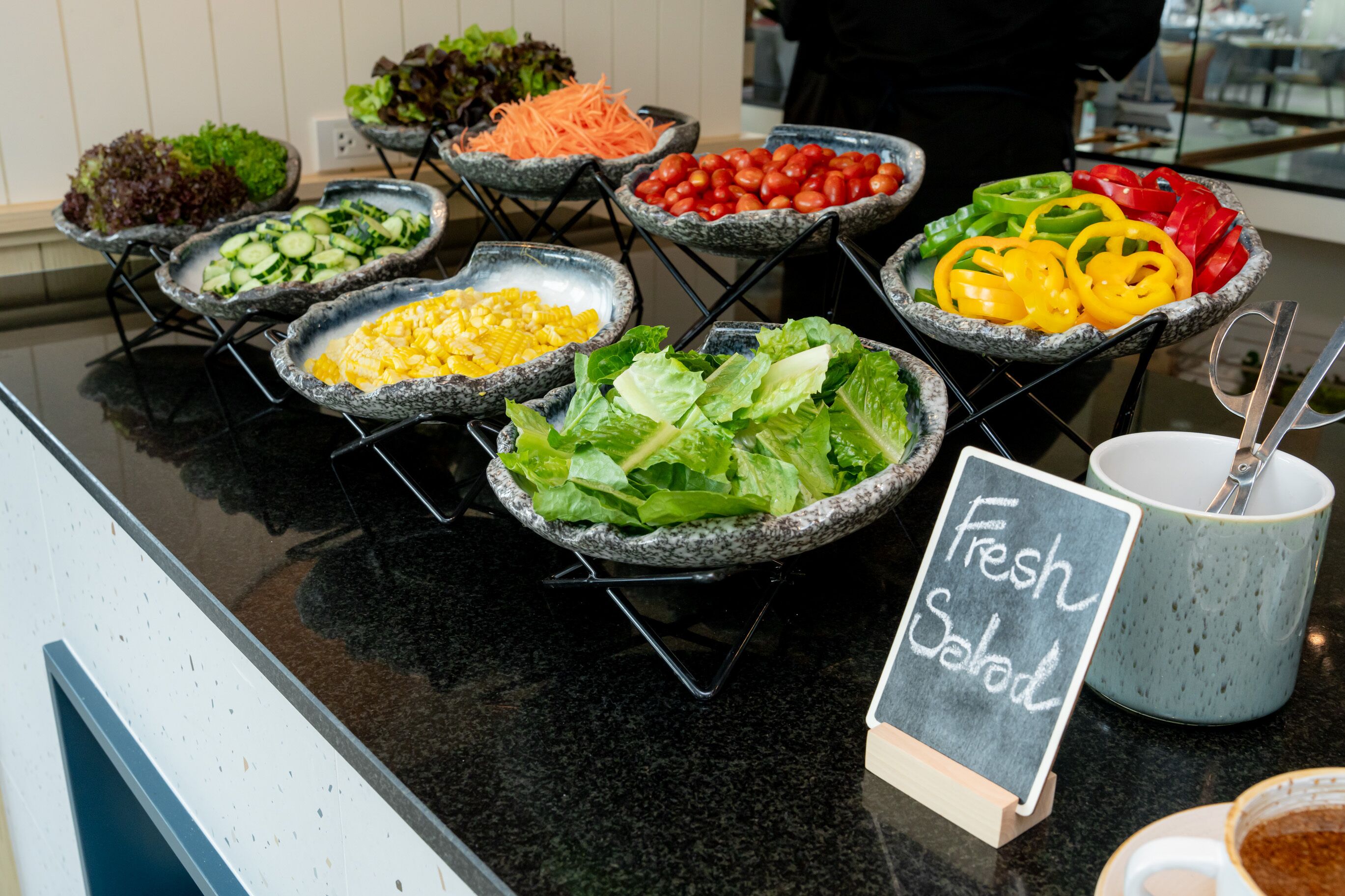 A buffet with various fresh salads and vegetables.