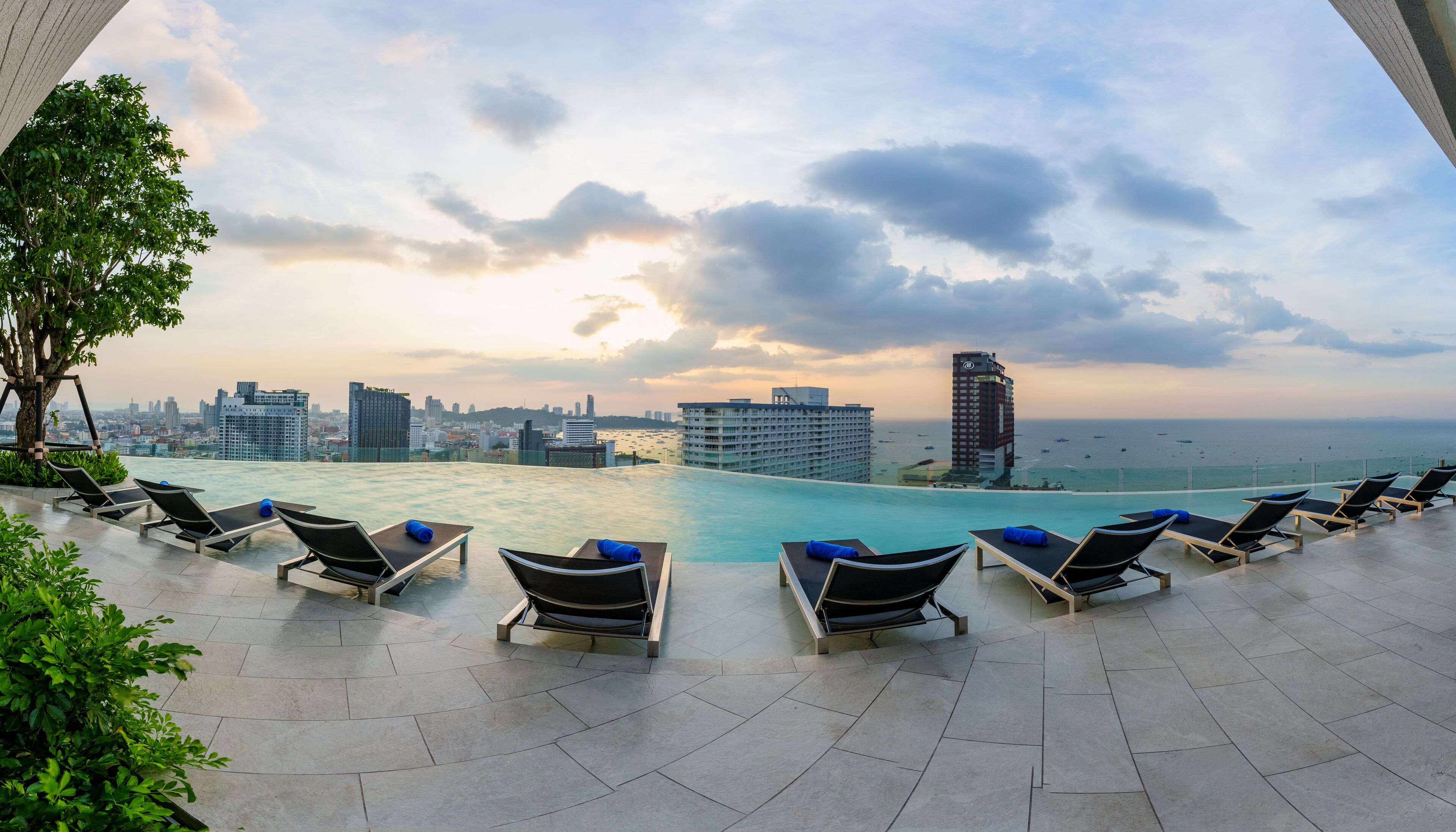 Ein Poolbereich auf dem Dach mit Liegestühlen und Blick auf die Stadt.