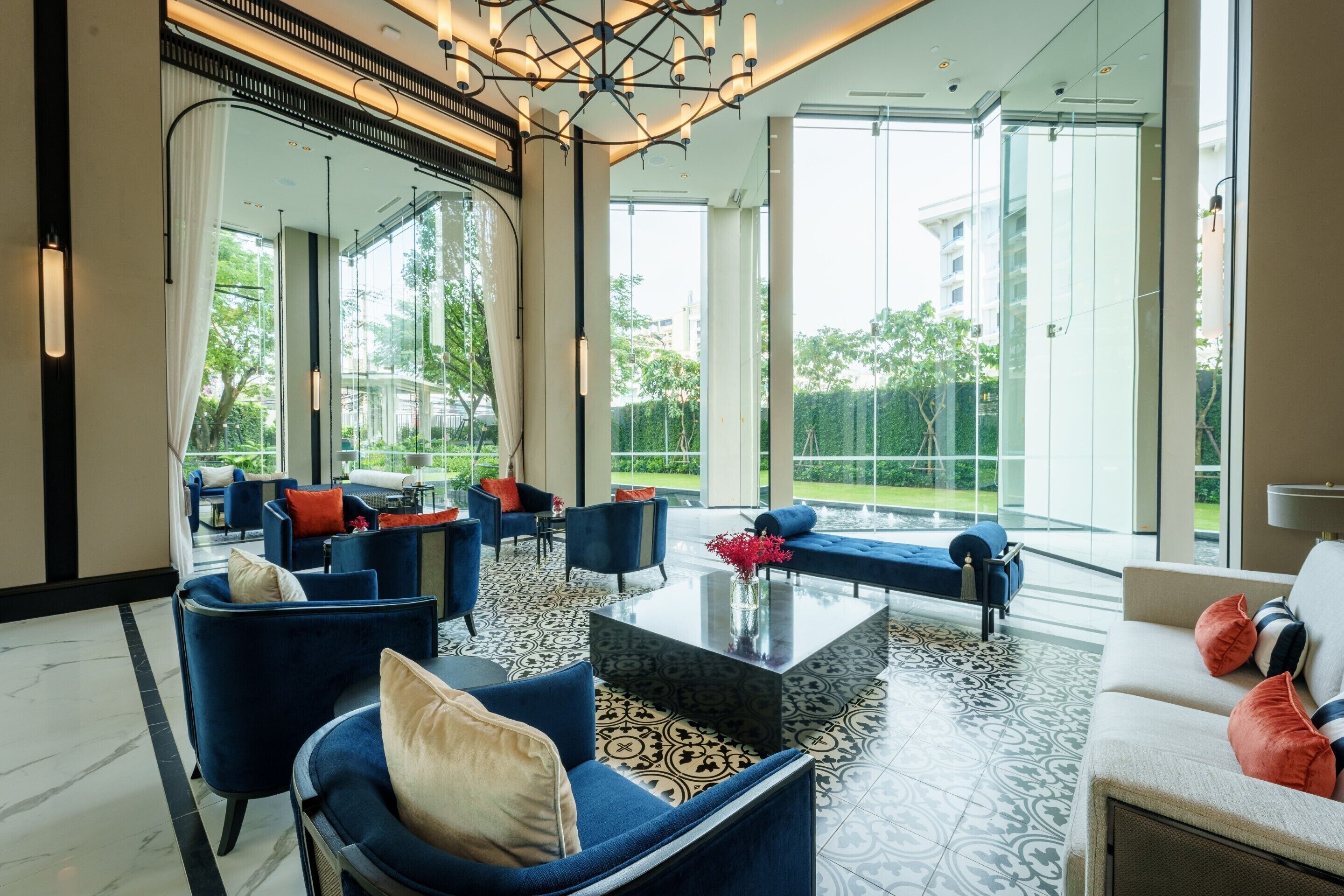 A spacious living area with modern furniture, large windows, and a view of greenery outside.