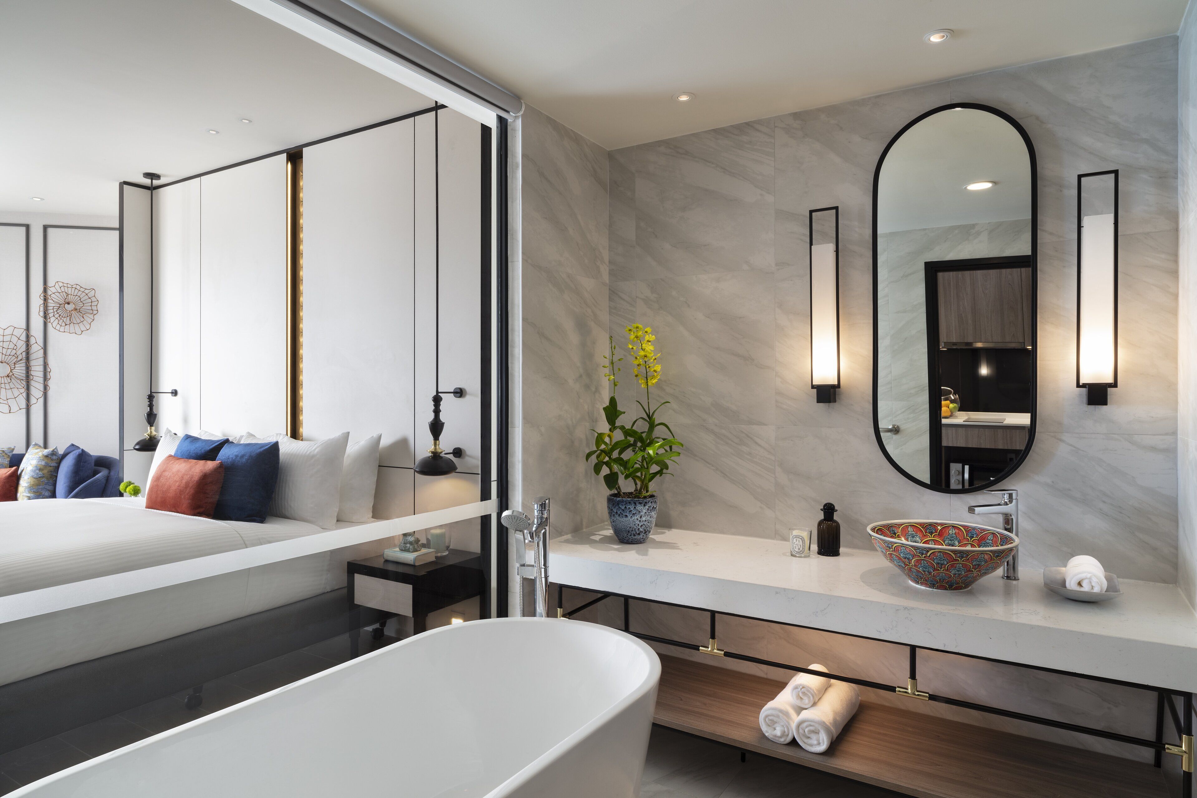 Une salle de bain moderne avec une baignoire sur pieds, un meuble-lavabo en marbre et un grand miroir.