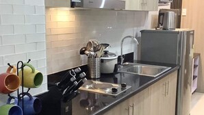 A modern kitchen with black countertops, stainless steel appliances, and a white tiled backsplash.