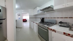 Uma cozinha moderna com eletrodomésticos de aço inoxidável, painel de azulejos e uma área de jantar visível ao fundo.