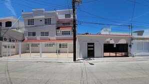 Um edifício com portão fechado, várias janelas e uma pequena construção anexa com telhado vermelho.