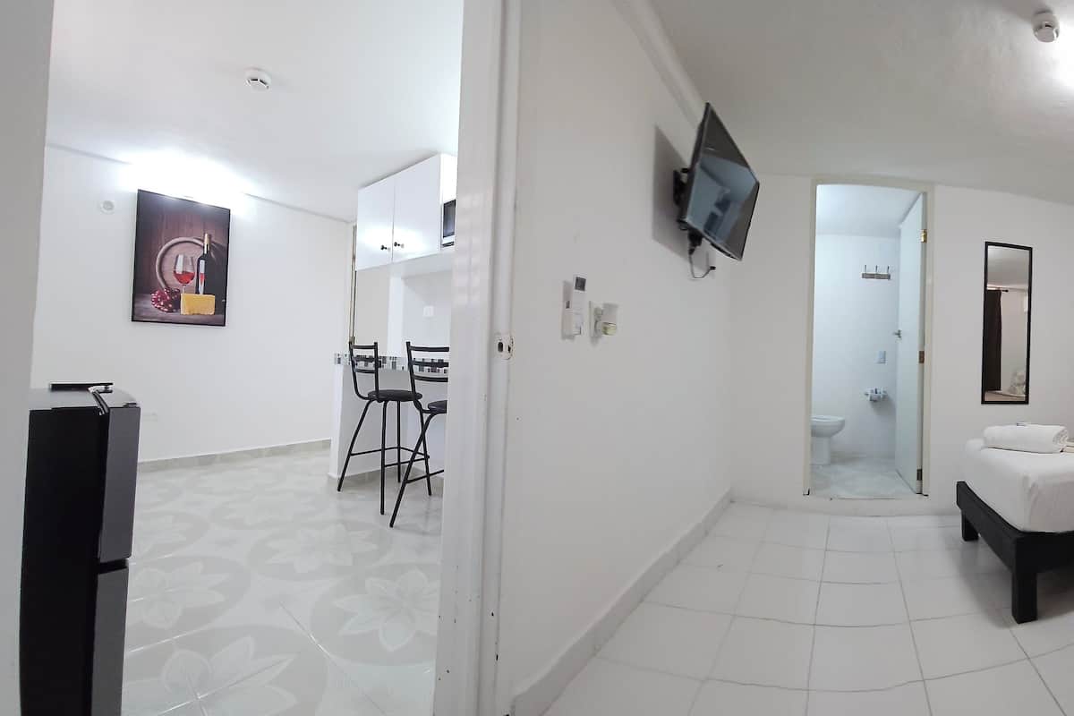 Habitación de hotel con dos camas, televisión, baño y zona de comedor.