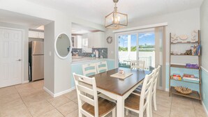 A modern kitchen with a dining area, a built-in refrigerator, and a large window offering a view of the outdoors. - Seaglass Shores, Steps to the Beach (Cape Canaveral)