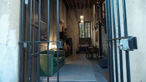Vista interior de una habitación con un sofá verde, una mesa de comedor y una lámpara colgante.