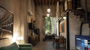 Una sala moderna con sofá, comedor y televisor mostrando la interfaz de un servicio de transmisión.