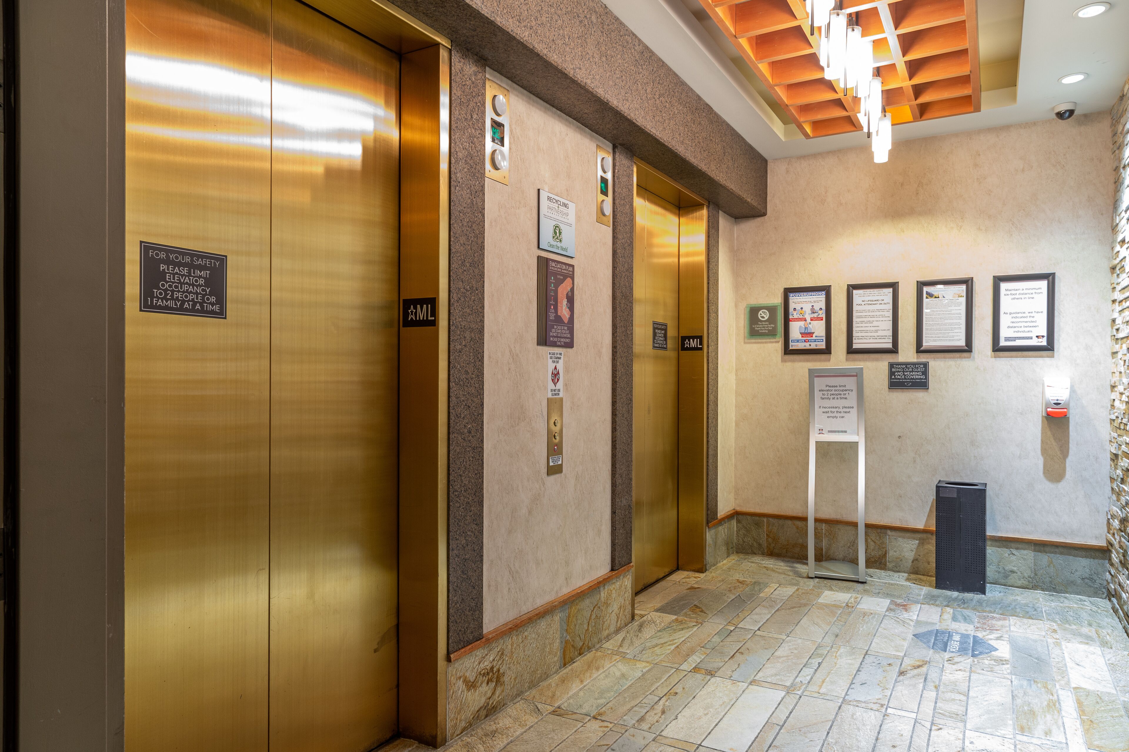 An elevator area with metallic doors, safety instructions, and informational posters on the walls.