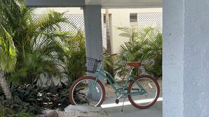 A covered outdoor area with a bicycle, gravel path, and potted plants.