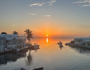 Marina com barcos atracados, pôr do sol e edifícios com varandas.