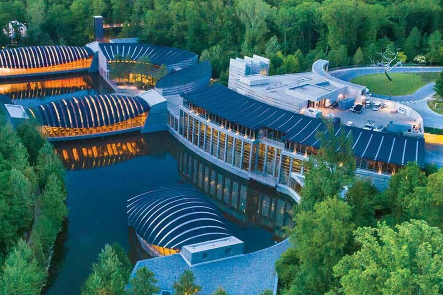 Ein Hotel am Wasser mit mehreren Gebäuden, einem zentralen Innenhof und einem umliegenden Wald.