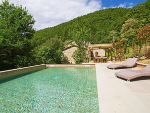 A clear pool with lounge chairs, a stone building, and a forested hillside. - Beautiful private villa for 15 guests with WIFI, hot tub, private pool, TV, patio and pets allowed (Sansepolcro)