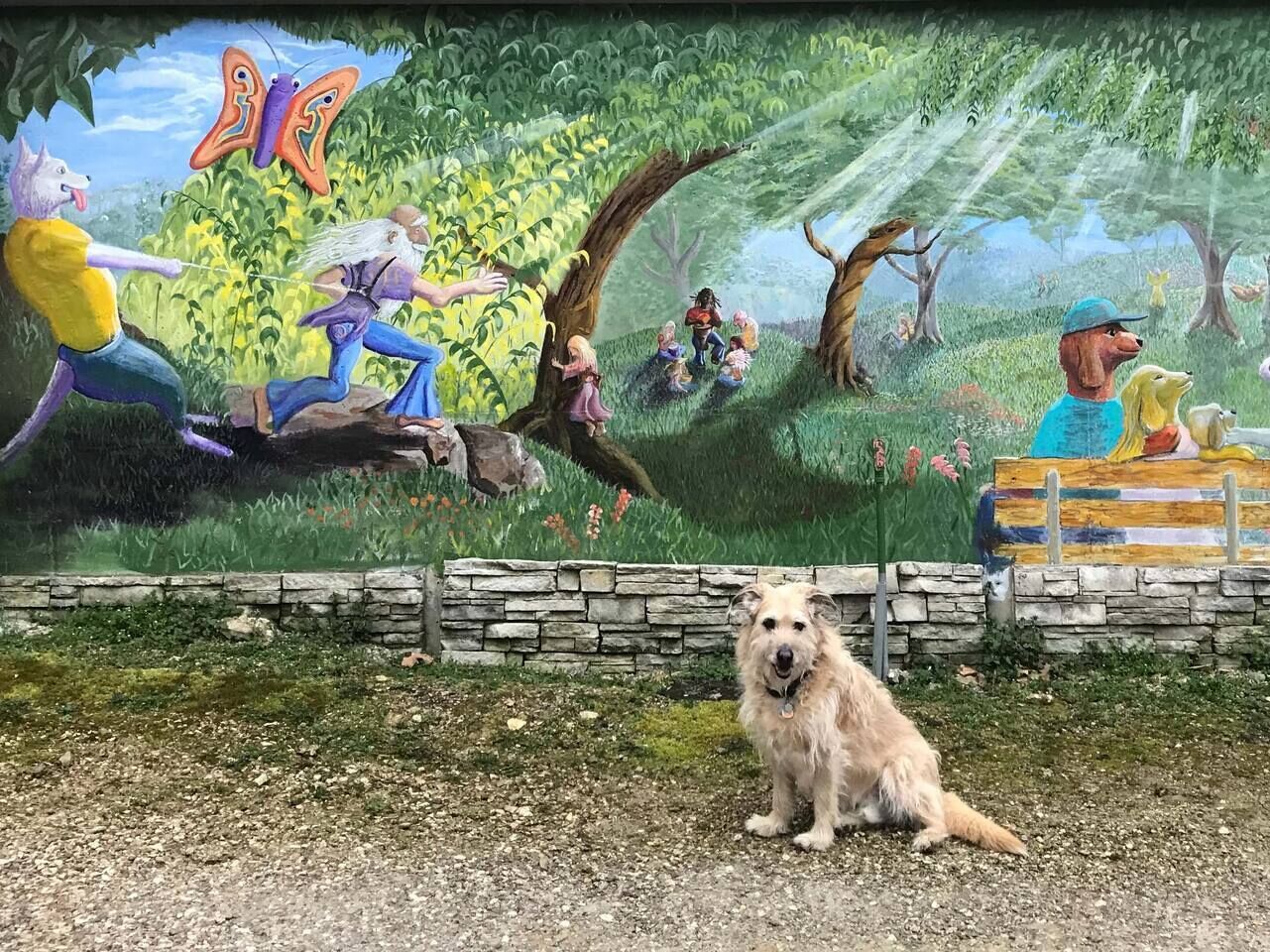 A mural with a dog in front of a stone wall.