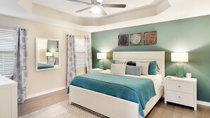 Ein Schlafzimmer mit Bett, Nachttischen, Deckenventilator und Wandbildern.