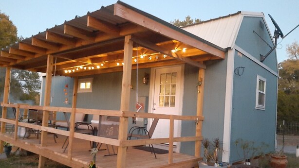 A small house with a wooden porch and string lights.