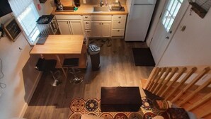 A compact living space with a kitchenette, a dining area, and a bed with a patterned blanket.