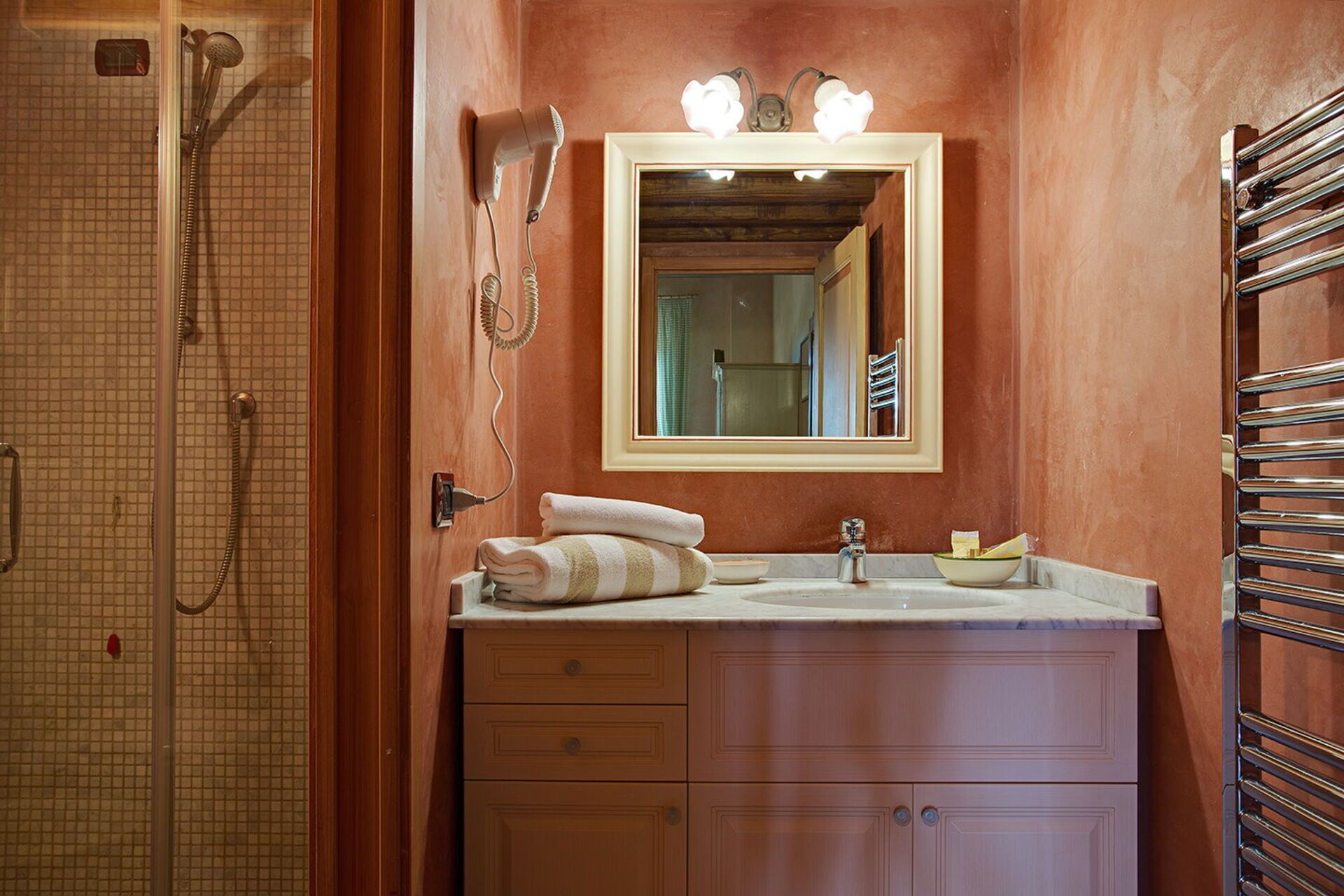 A bathroom with a shower, a sink, a mirror, and a towel rack.
