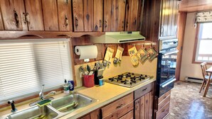 A kitchen with wooden cabinets, a stainless steel sink, a gas stove, and a window with blinds. - Lake of the Ozarks Secluded Vacation Home Waterfront with a Covered Dock. (Stover)