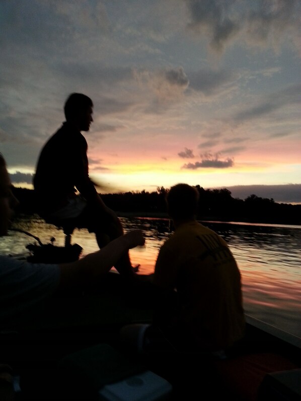 Silueta de una persona sentada en un bote con un atardecer de fondo.
