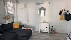 Ett modernt vardagsrum med en mörkgrå hörnsoffa, ett vitt sidobord och en rund spegel på väggen.