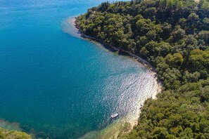 An aerial view of a coastal area with a clear beach and dense forest. - Villa Anastar in Corfu (Corfu)