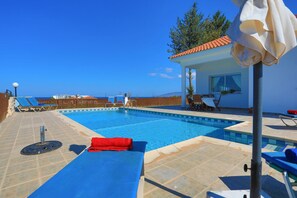 Une piscine recouverte d’une bâche bleue, une serviette rouge et une clôture en bois en arrière-plan.