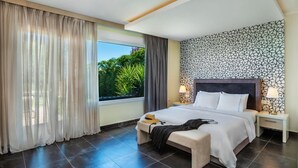 A modern hotel room with a large bed, two bedside tables, a bench, and a view of greenery outside. - Sunny Villa Grande in Kassandra (Kassandra)