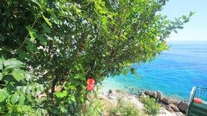 A coastal view with a clear blue sea, rocky shoreline, and a staircase leading down to the beach. - Alexandra Studio in Katavolos (Corfu)