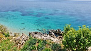 A coastal landscape with clear turquoise waters, rocky shoreline, and lush greenery. - Alexandra Studio in Katavolos (Corfu)