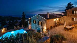 A stone house with a pool and outdoor seating, surrounded by greenery and a clear sky. - Villa Katerini in Paxi (Paxos)