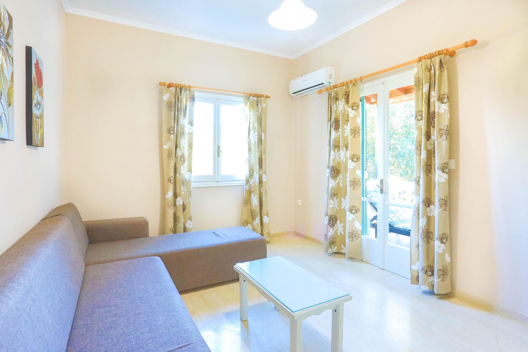 A living room with a sofa, a glass-top table, and floral curtains.