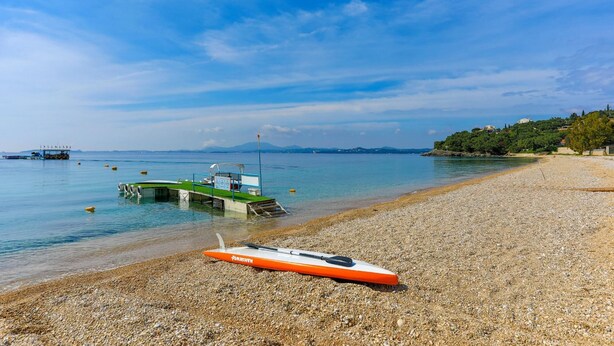 A pebble beach with a kayak and a boat docked in the water.