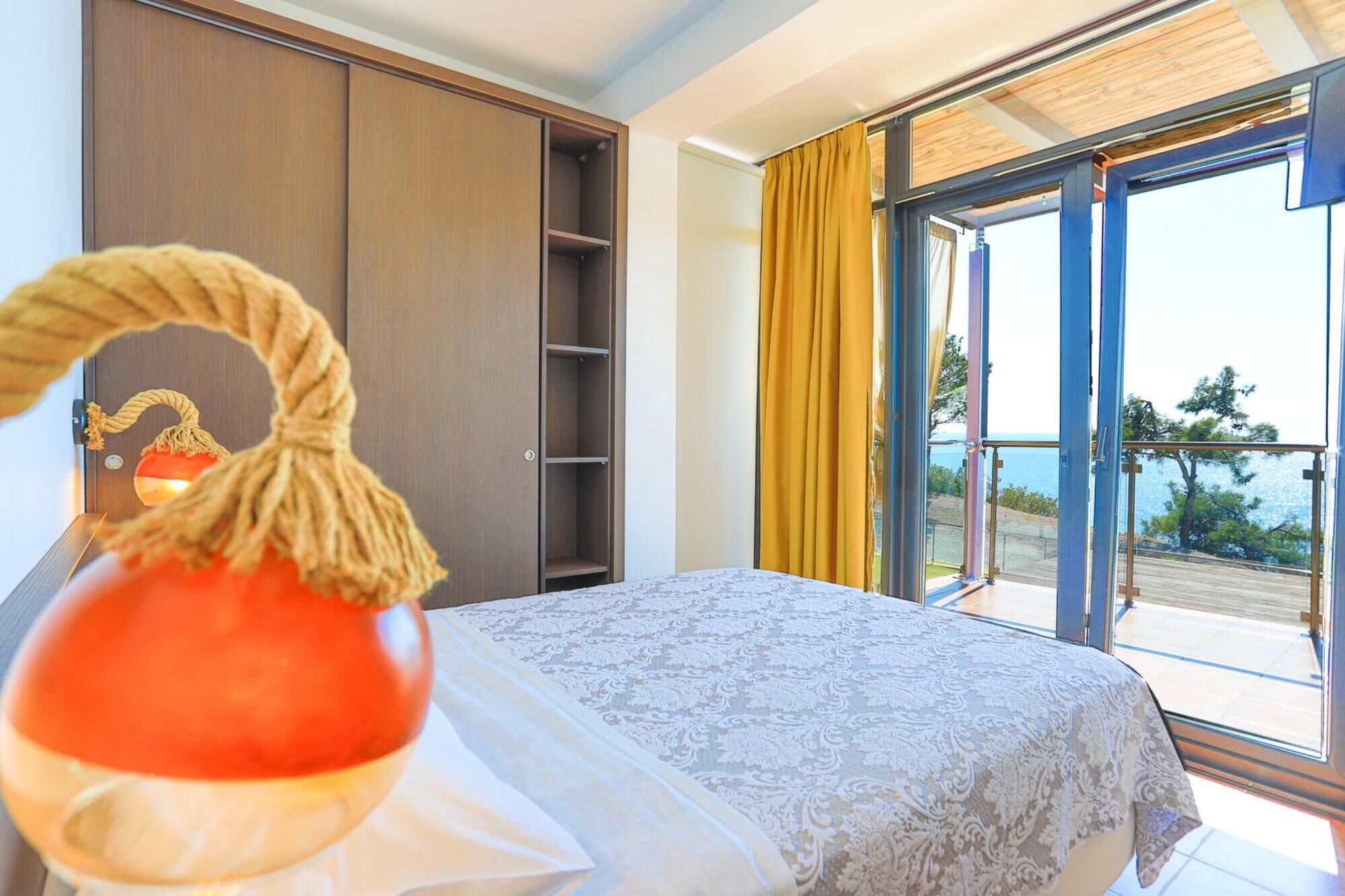 A bedroom with a bed, a wardrobe, and a balcony with a view.