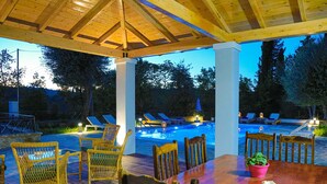 An outdoor pool area with lounge chairs and a wooden deck. - Achilleion Forest Villa (Corfu)