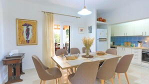 A dining area with a table set for four, surrounded by chairs, a vase with dried plants, and a painting on the wall. - Achilleion Forest Villa (Corfu)
