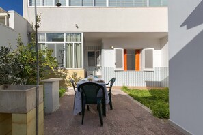 An outdoor patio with a table and chairs, a small garden, and a building with windows and shutters. - 2689 Dalia House by Barbarhouse (Melendugno)