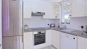 A modern kitchen with white cabinets, stainless steel appliances, and a window providing natural light. - Villa Irina Polis in Polis (Polis)