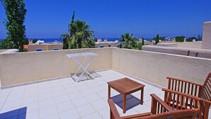 A rooftop terrace with a table and chairs, a view of the sea, and some greenery. - Villa Irina Polis in Polis (Polis)