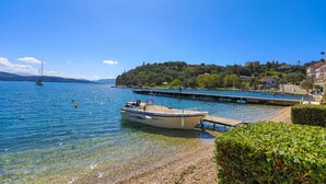 A boat docked at a pier with clear water and a distant shoreline. - Paola House in (Corfu)