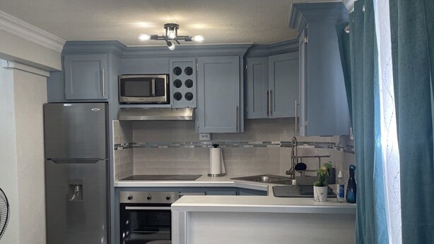 A modern kitchen with grey cabinets, stainless steel appliances, and a central island.