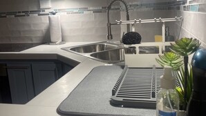 A kitchen with a sink, faucet, and a bottle of hand sanitizer.