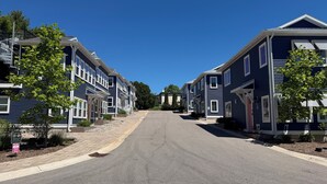 A residential street with houses on both sides, a clear sky, and a paved road. - Riverwalk One Condo with rooftop deck (Charlevoix)