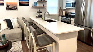 A modern kitchen with a central island, bar stools, a stove, and a refrigerator. - Riverwalk One Condo with rooftop deck (Charlevoix)