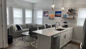 A modern kitchen with a central island, a built-in sink, and a dining area. - Riverwalk One Condo with rooftop deck (Charlevoix)