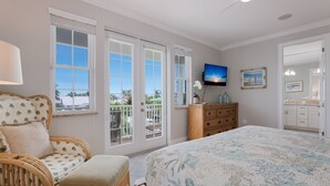Quarto com uma cama grande, uma cadeira de vime, um penteado e uma TV na parede.